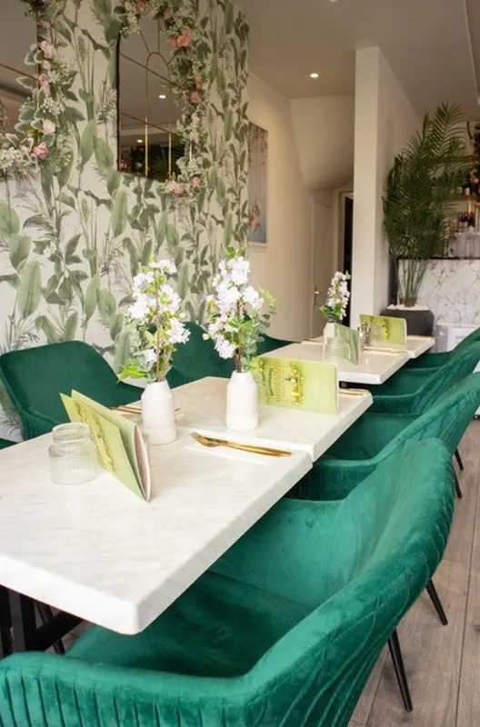 Tables en marbre blanc, fleurs fraîches et fauteuils en velours vert émeraude
